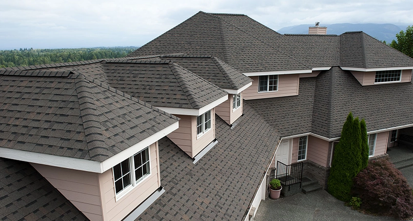 Asphalt shingle roof on a large suburban house with dormer windows.