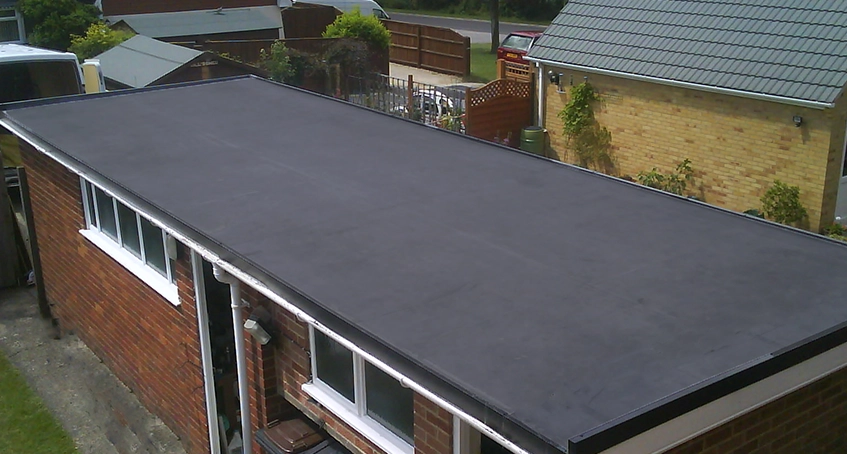 Flat low-slope roofing with surrounding buildings and greenery.