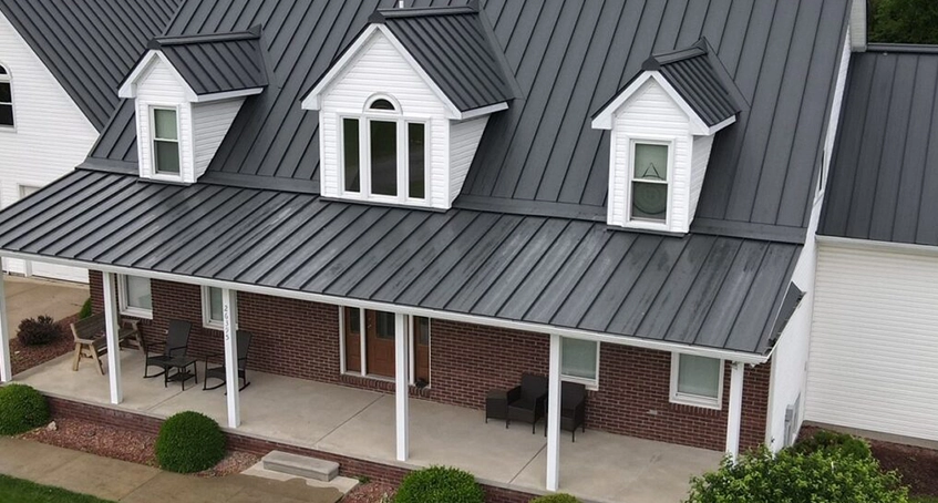 Large house with black metal roofing and white dormer windows.